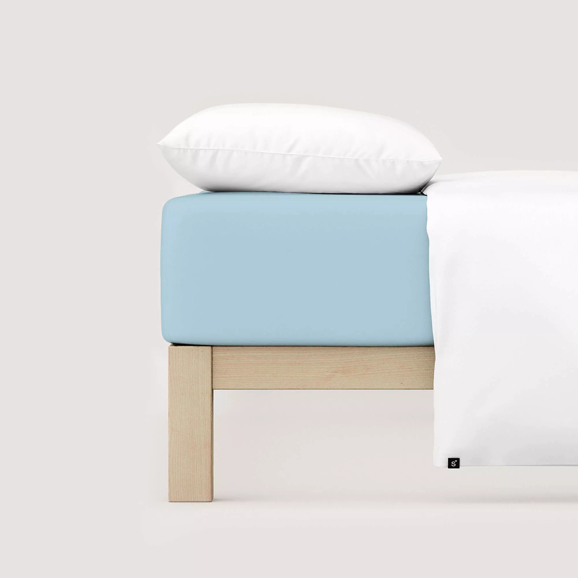 Spannbettlaken Pure von Schlafgut in Farbe blue light aus 95% Bio-Baumwolle und 5% Elasthan auf Bett mit Kissen und Decke