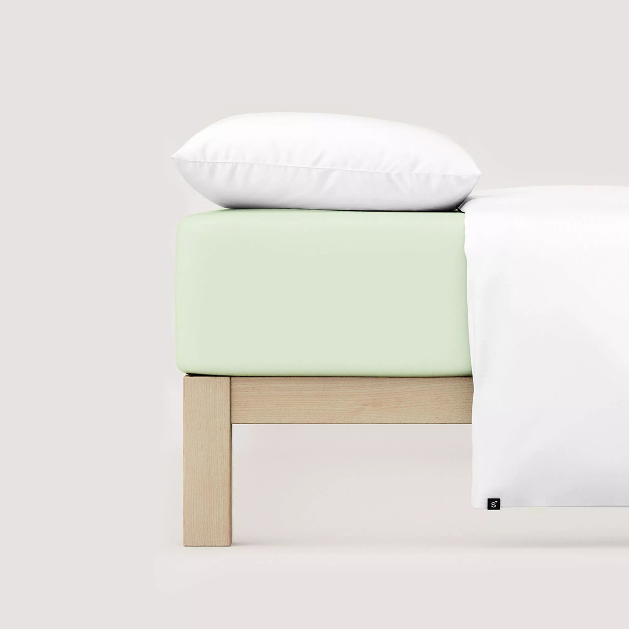 Spannbettlaken Pure von Schlafgut in Farbe green light aus 95% Bio-Baumwolle und 5% Elasthan auf Bett mit Kissen und Decke