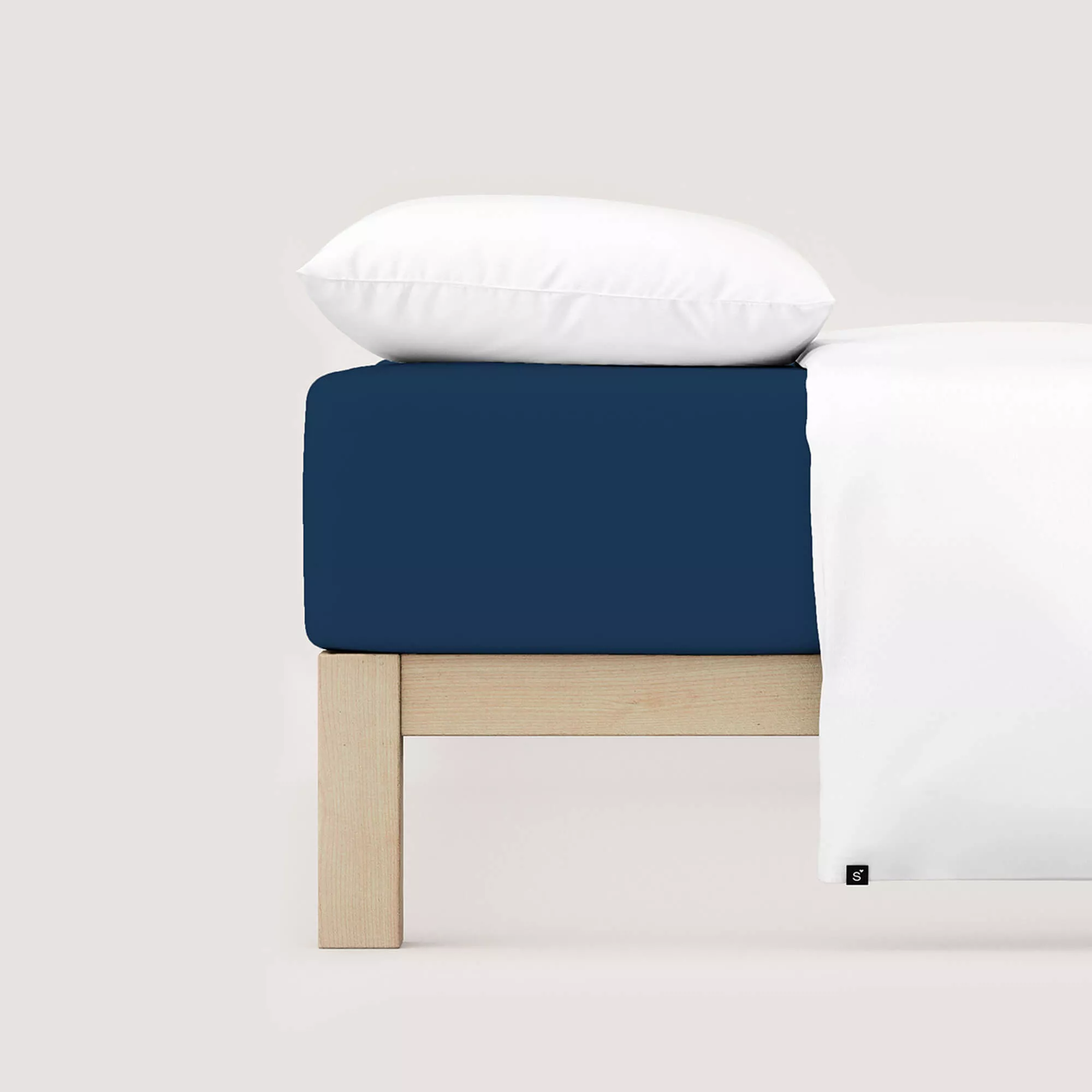 Spannbettlaken Pure von Schlafgut in Farbe blue deep aus 95% Bio-Baumwolle und 5% Elasthan auf Bett mit Kissen und Decke