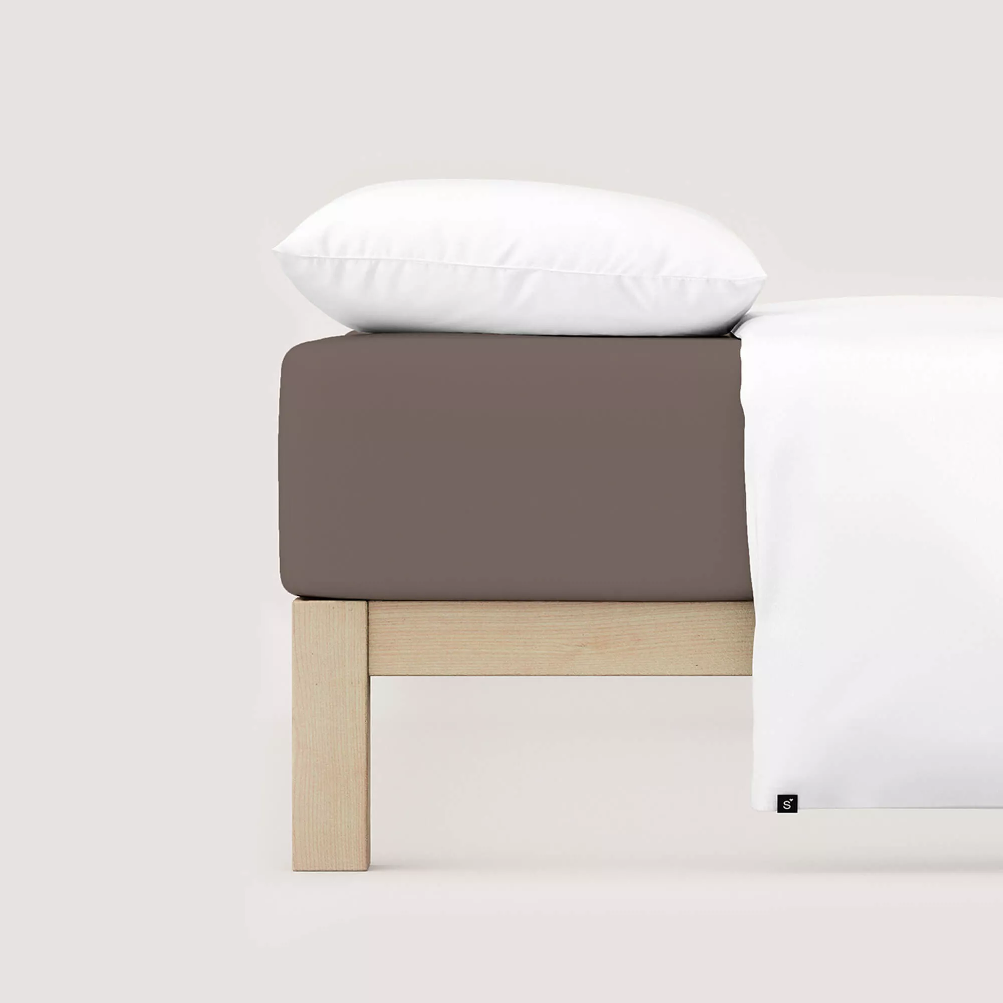 Spannbettlaken Pure von Schlafgut in Farbe sand deep aus 95% Bio-Baumwolle und 5% Elasthan auf Bett mit Kissen und Decke