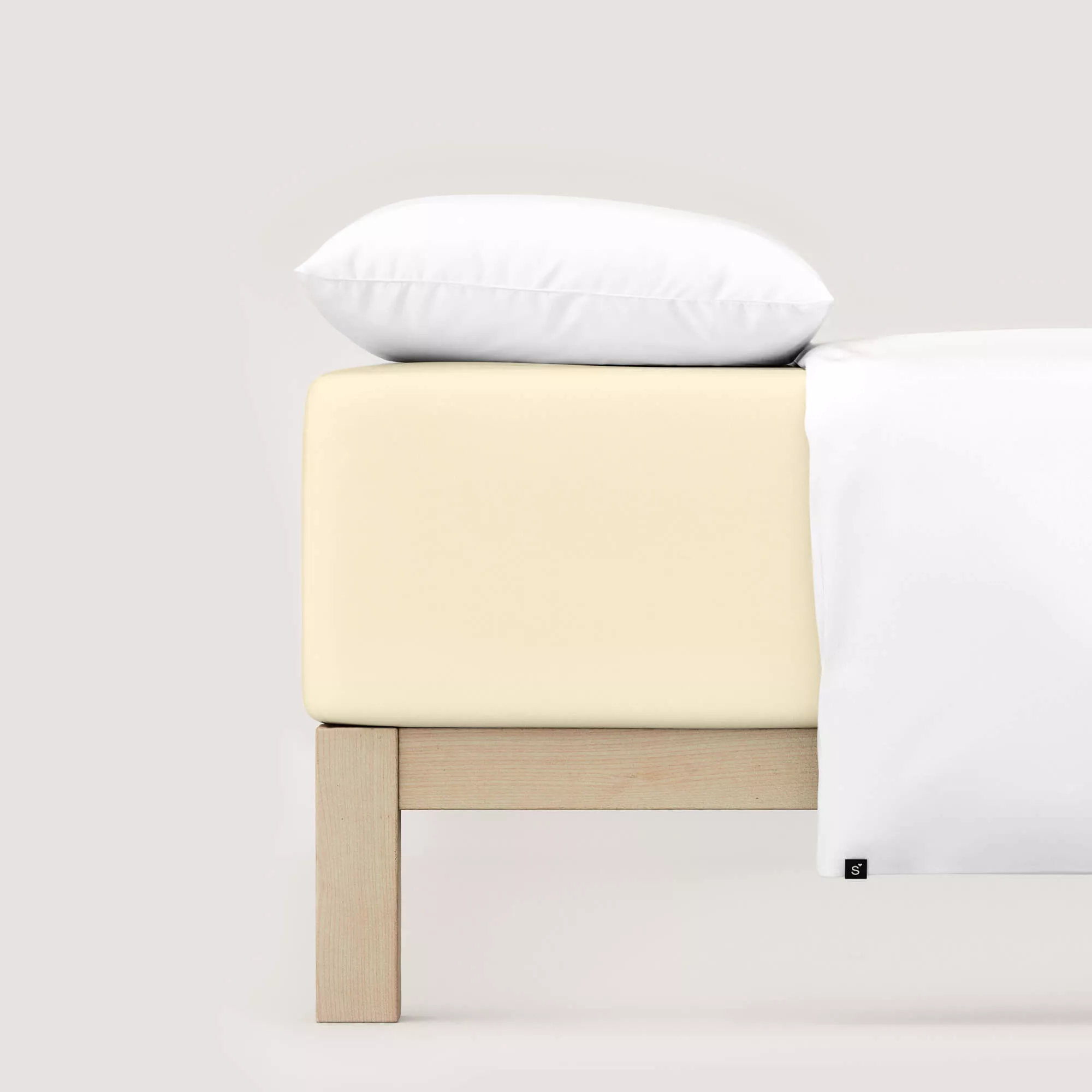 Spannbettlaken Pure Boxspring von Schlafgut in Farbe yellow light aus 95% Bio-Baumwolle und 5% Elasthan auf Bett mit Kissen und Decke